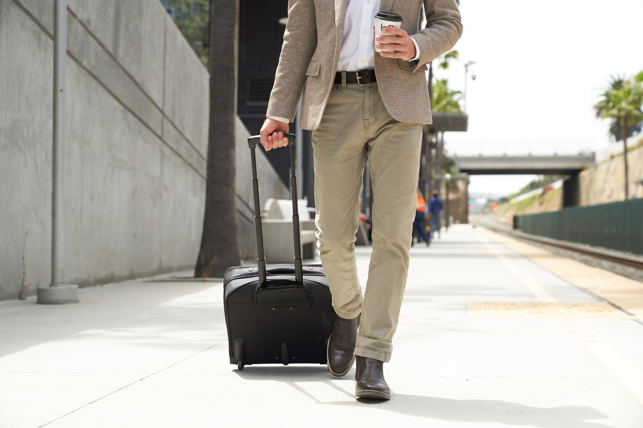 Man walking with suitcase and coffee at station