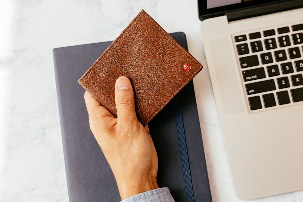 man holding a leather bifold wallet