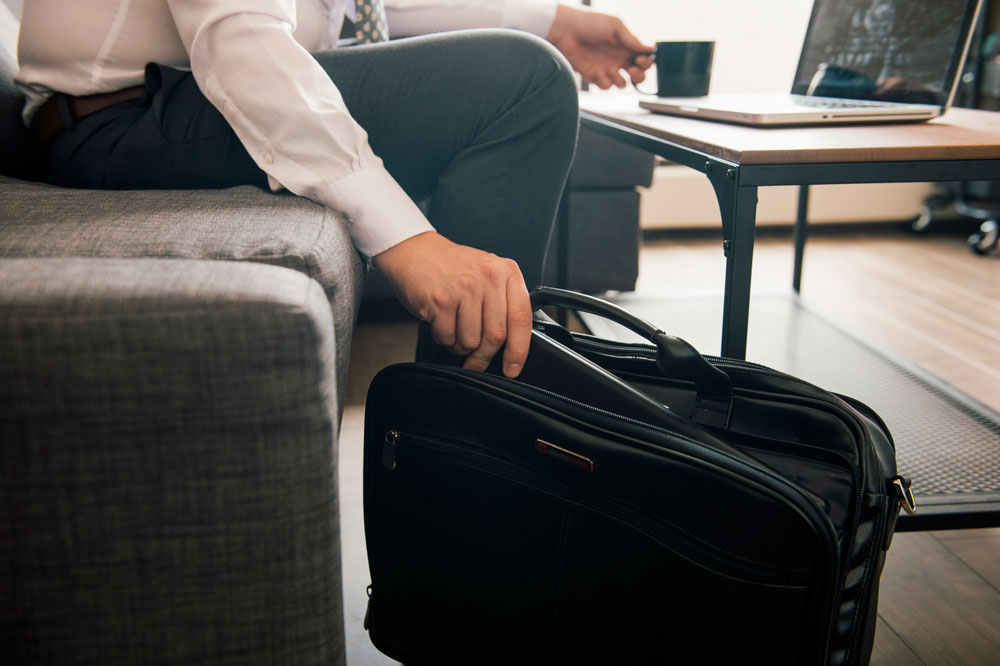 man removing laptop from his messenger bag