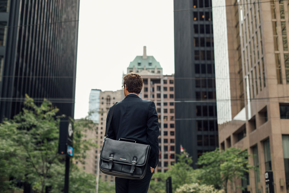 man standing with a leather messenger bag 